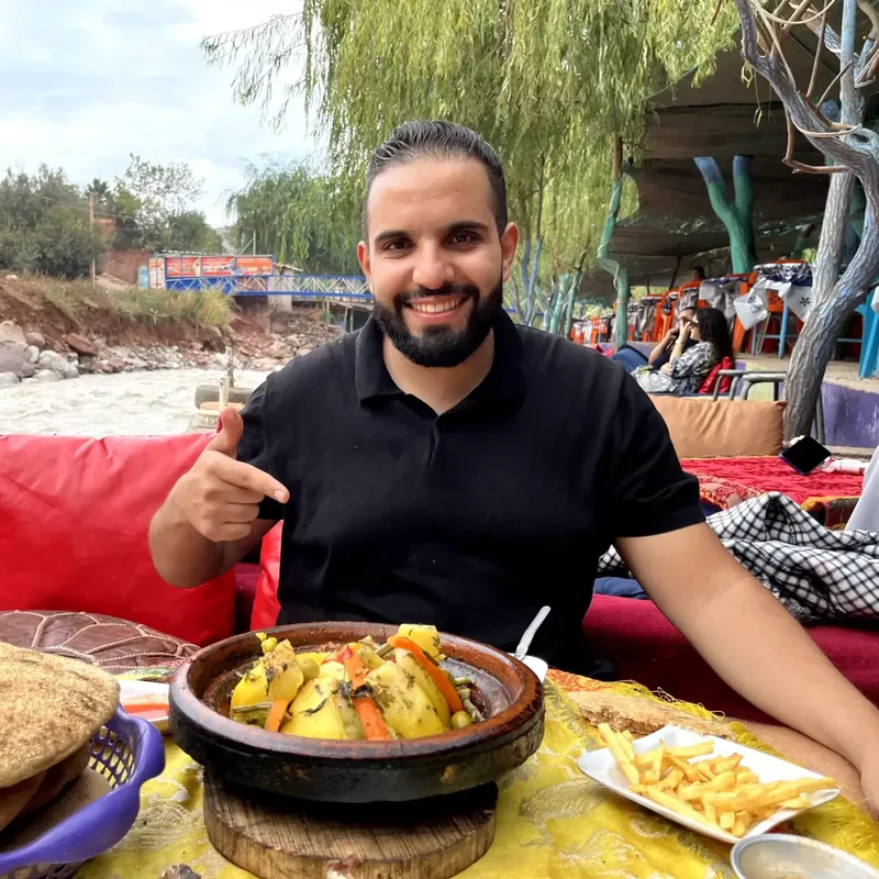 Khalid, fondateur d'Accromaroc, attablé devant un tajine au bord d'un oued